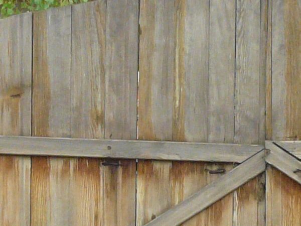 Large wooden gates in light grey tone with arching top and crossbar at center.